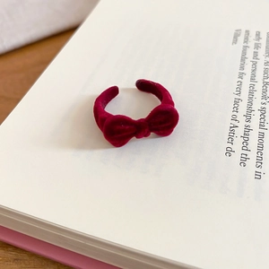 Detail of burgundy velvet bow ring resting on a vintage book page with soft natural lighting