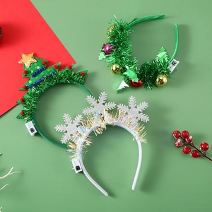 Detailed view of LED Christmas headbands with glowing trees and wreaths on festive background