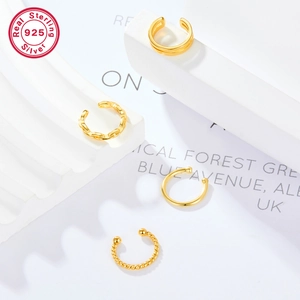 Macro view of four assorted 925 sterling silver gold-plated ear cuffs on white pedestals