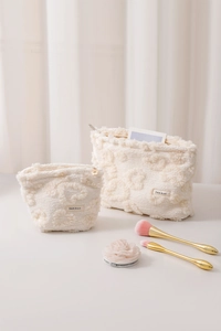 Detail of cream white plush cosmetic bags in two sizes with soft floral texture