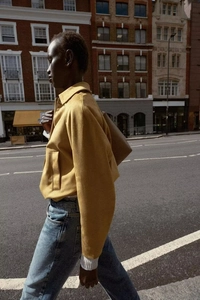 Detail of yellow faux suede jacket featuring a retro lapel design and zip-up front