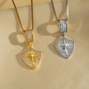 Elegant gold and silver shield pendant necklaces with zircons on soft beige fabric