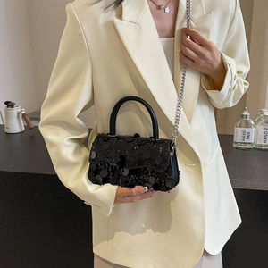 Detail of a chic black sequined square bag featuring a top handle and silver chain strap