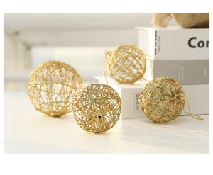 Detail showing golden glittery hollow wire Christmas balls on a minimalist white surface