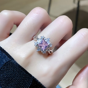 Macro shot of pink square gemstone ring with floral cluster diamonds on model finger