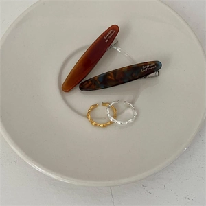 Detailed view of acetate tortoiseshell hair clips and metal rings on a ceramic plate