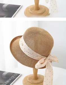 Détail du chapeau de paille avec ruban à pois et logo métallique doré élégant