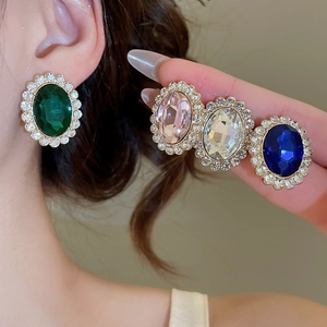 Detailed view of oval rhinestone earrings in dark green, pink, blue, and clear white