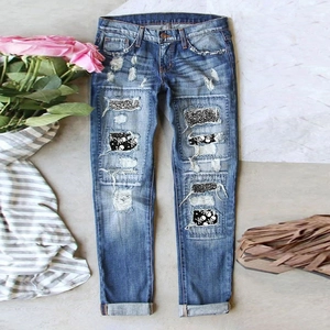 Blaue Jeans mit Distressed-Look, Totenkopf-Patches und Pailletten auf Steinboden
