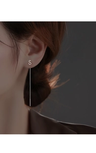 Detail view of minimalist silver S-shaped long threader earrings worn by a model