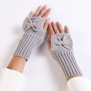 Close-up of grey knitted fingerless gloves with bow detail and soft wool texture