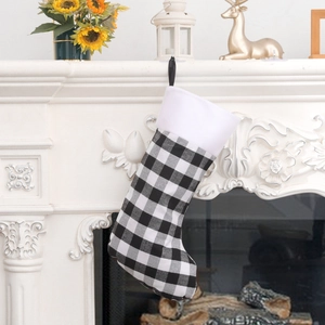 Plaid Christmas stocking in black and white hanging on fireplace for holiday decoration