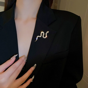 Detailed close-up of a gold-plated snake brooch with sparkling crystals on a black suit lapel