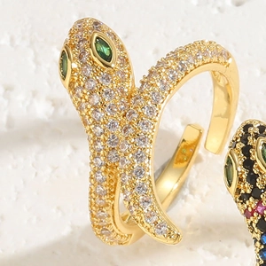 Macro detail of a 14K gold snake ring featuring green gem eyes and pavé zircon stones