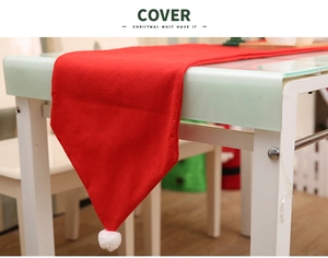 Detail of red festive table runner with white plush ball shaped like a Santa hat