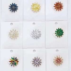 Detail view of 9 crystal snowflake brooches in various colors on jewelry display cards