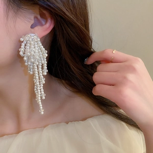 Gros plan de longues boucles d'oreilles à franges perlées portées par un mannequin