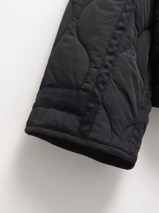 Detail of black quilted jacket cuff featuring water ripple patterns and drawstring design