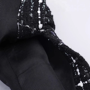 Detailed view of tweed fabric texture with metallic silver fibers and black lining