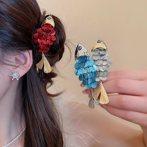 Detailed macro view of fish-shaped hair clips with sequins and gold metallic finish