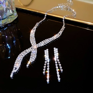 Detail shot of sparkling rhinestone necklace and earring set on black reflective surface