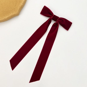 Detailed close-up of a deep red velvet bow hair clip with elegant long streamers