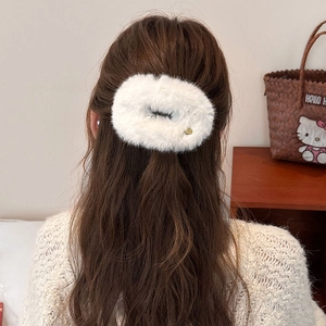 Close-up of a white plush hair clip worn on long brown hair for an elegant look