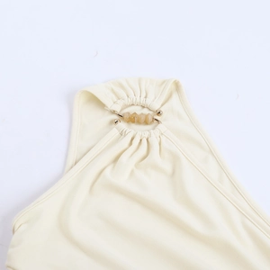 Detailed close-up of halter neckline with gold ring and amber resin beads on beige dress
