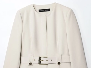 Détail d'un blazer crème avec ceinture en tissu et œillets en métal doré de haute qualité