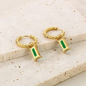 Boucles d'oreilles créoles dorées avec pendentifs rectangulaires verts sur travertin