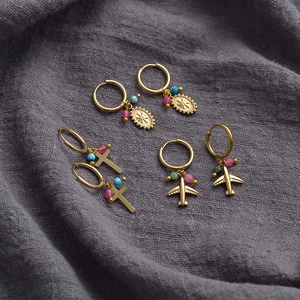 14K gold-plated hoop earrings with beaded cross, airplane, and oval charms on grey fabric