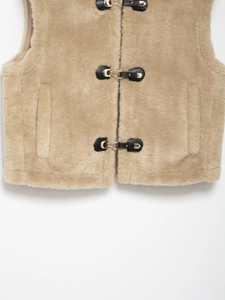 Detail of khaki faux fur vest with black leather trim and golden metal buckles