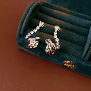 Detailed close-up of silver snake earrings with zircons in a green velvet jewelry box