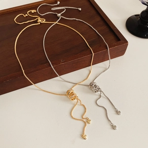 Close-up of gold and silver zircon circle necklaces with small heart pendant on wood