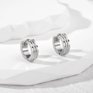 Detail of silver stainless steel hoop earrings with double frosted grooves on white stone