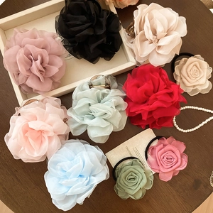 Detailansicht bunter Chiffon-Blumen-Haarspangen und Haargummis auf einem rustikalen Holztisch