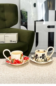 Detailed view of ceramic iris flower coffee cup and saucer on soft cream velvet background