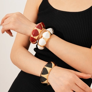 Detail view of retro wide geometric bangles with red, white, and black enamel finishes