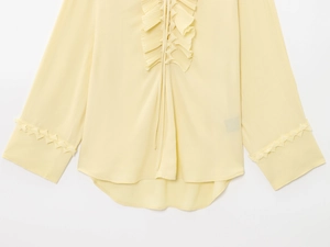 Detail of yellow chiffon top with ruffled hem and unique triangular lace cuffs on sleeves