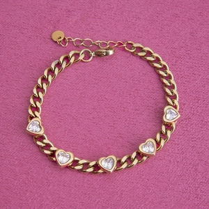 Detail of gold chain bracelet with five heart-shaped cubic zirconia on velvet background