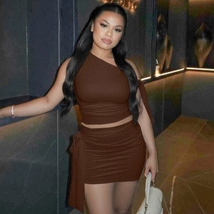 Detail of a brown one-shoulder knit top and ruched skirt set on a model in indoor setting