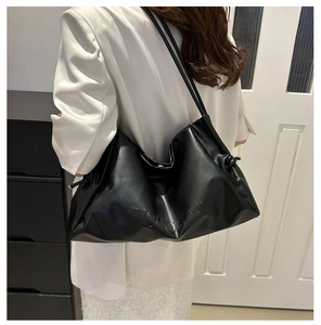 Side view of soft black cloud pleated tote bag with knot detail and embossed texture
