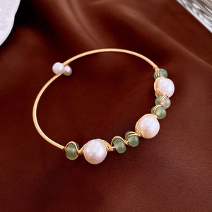 Macro detail of gold plated wire wrapped bracelet with freshwater pearls and green stones