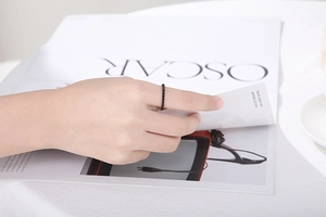 Detail of a black twisted rope texture stainless steel ring worn against a white magazine