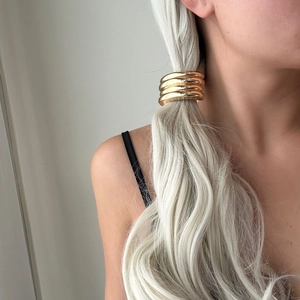 Close-up of a minimalist gold metal hair ring worn on a sleek ponytail by a model