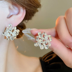 Elegant silver flower stud earrings with a hollow textured petal design in a minimalist style