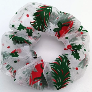 Detail of white mesh scrunchie with Christmas pine and red bow prints on white background