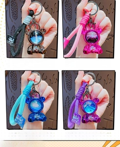 Detail showing space-themed bear keychains with colorful braided wrist straps in four colors