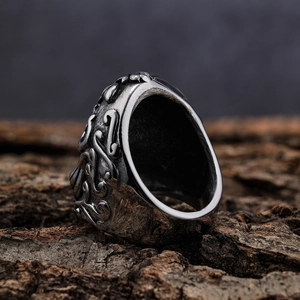 Vintage punk style stainless steel skull ring with carved textures on a rustic wood background
