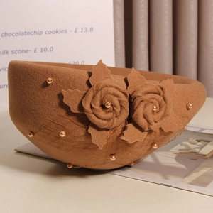 Detail of brown wool beret featuring elegant handmade fabric flowers and mesh veil